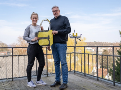 (WER) stehen auf einer Dachterrasse und präsentieren einer er upgecycelten Taschen in gelber und weißer Farbe